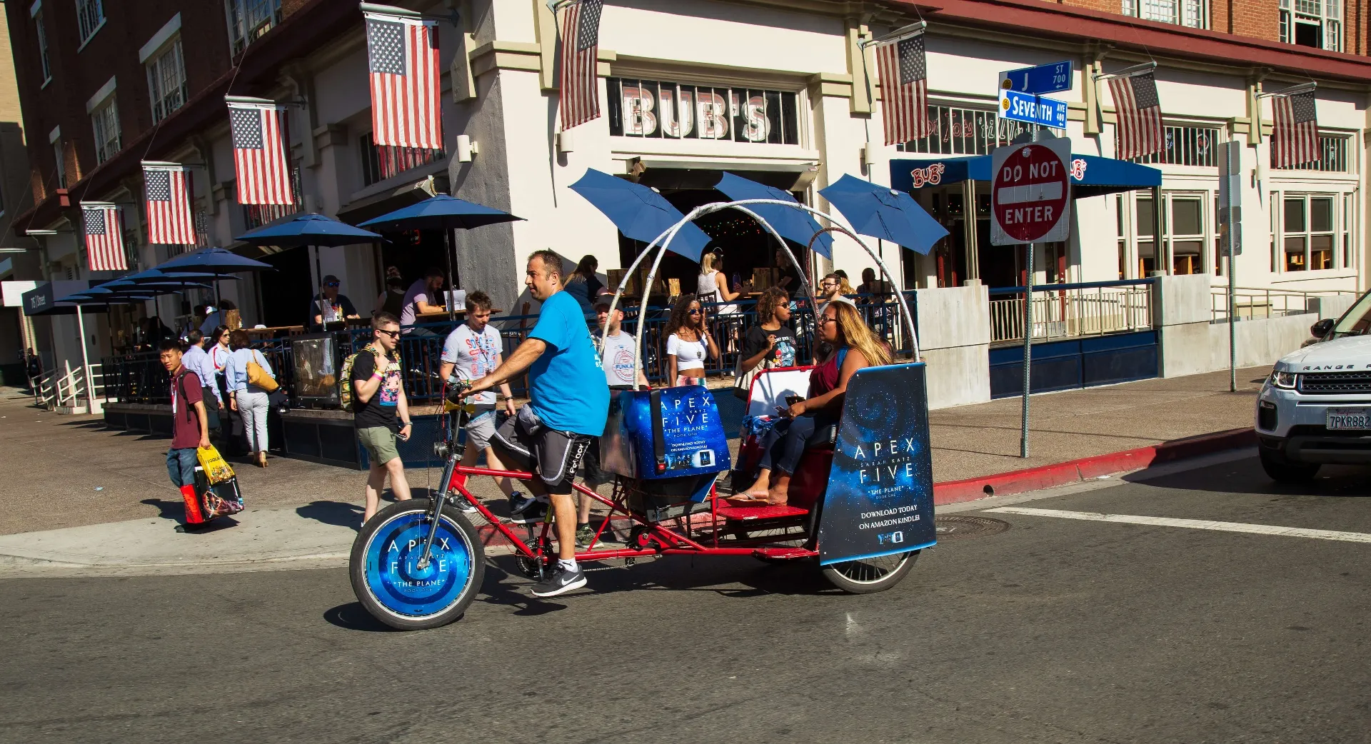 Apex Five branded pedicab carrying passengers past Gaslamp restaurants