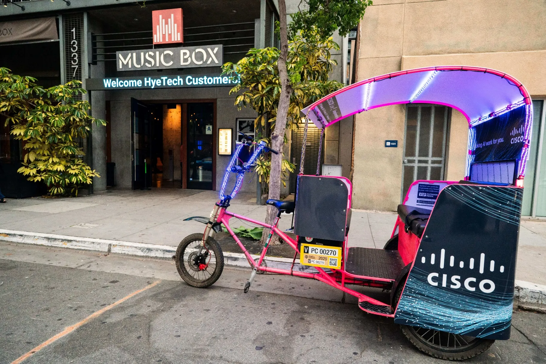 Cisco branded pedicab with LED lights parked outside Music Box venue in San Diego at night
