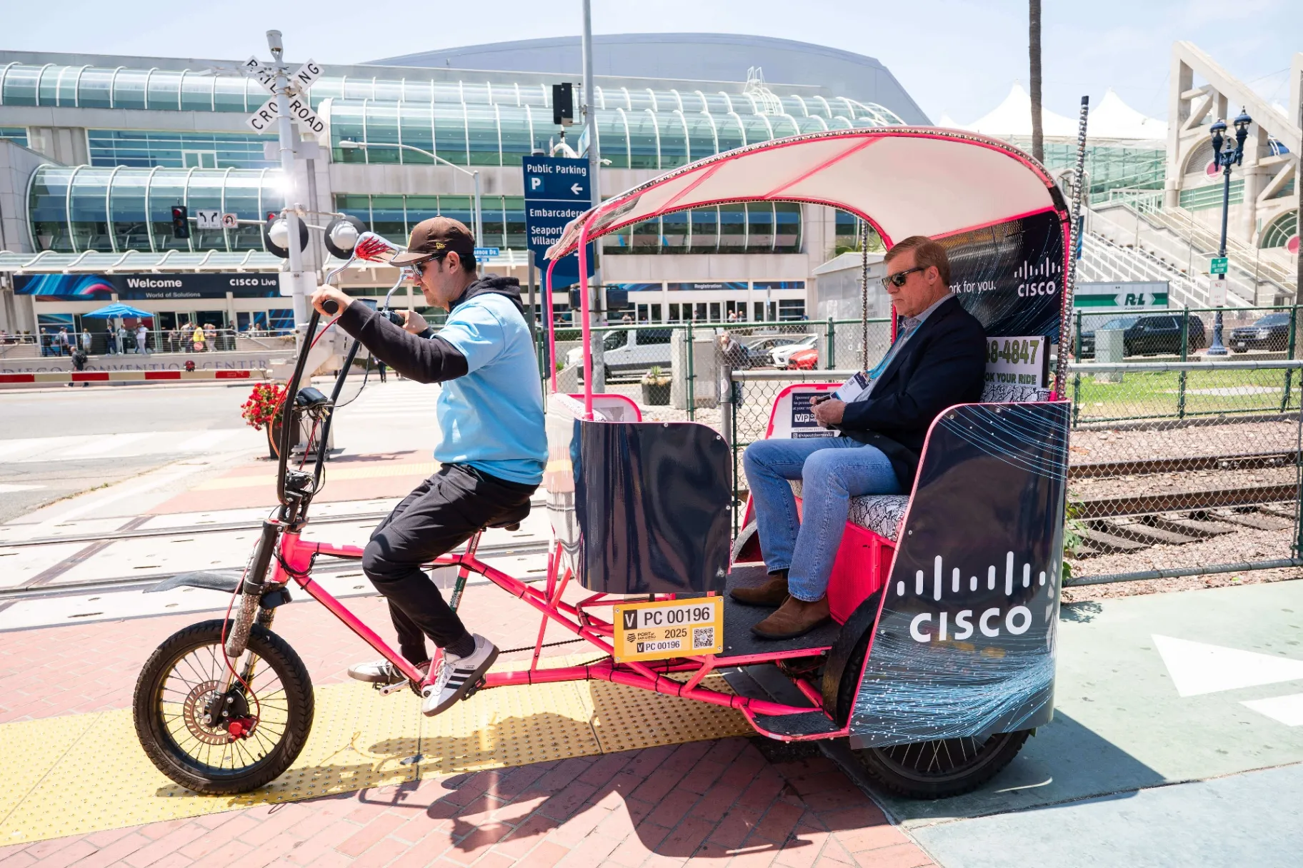 Cisco branded pedicab rider transporting convention attendee near San Diego Convention Center