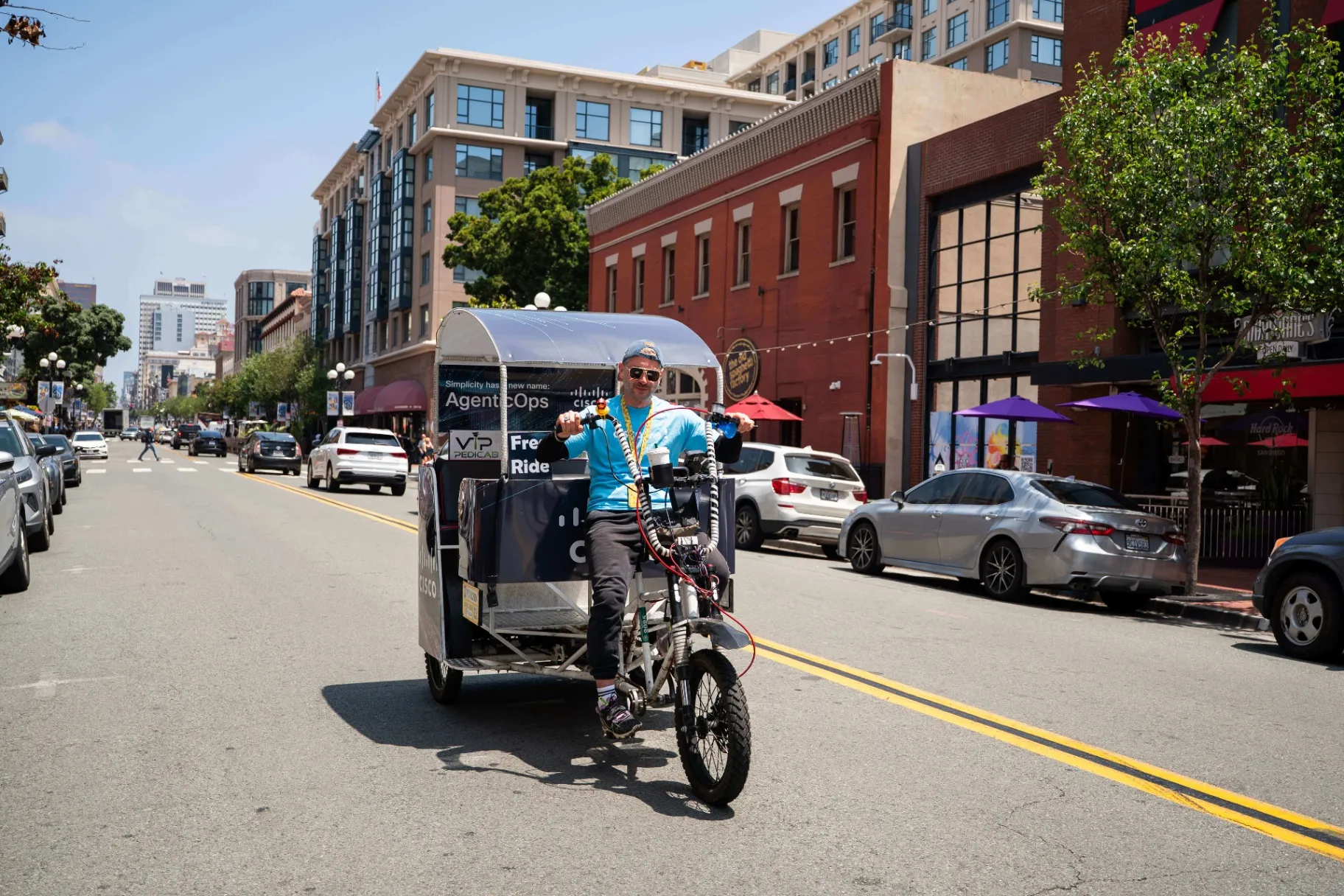 VIP Pedicab driver with Cisco advertising wrap riding through Downtown San Diego near Convention Center