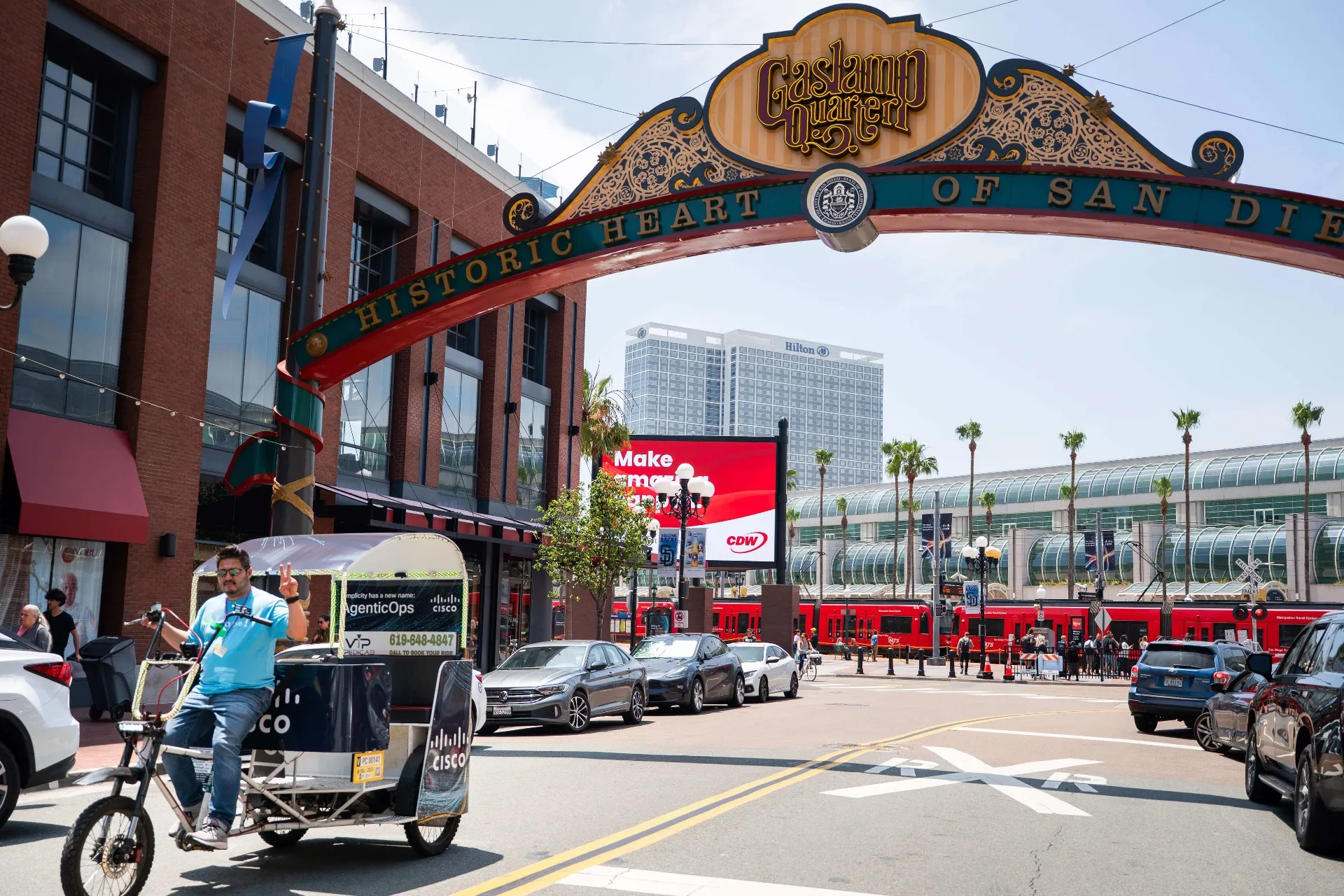 Cisco branded pedicab under Gaslamp Quarter arch with San Diego Convention Center in the background