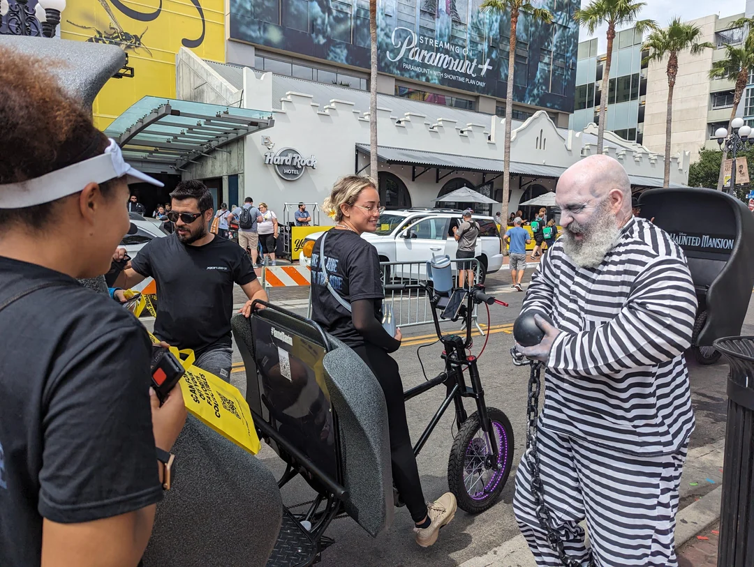 Haunted Mansion pedicab passenger experiencing costumed ghost actor ride-along at Comic-Con