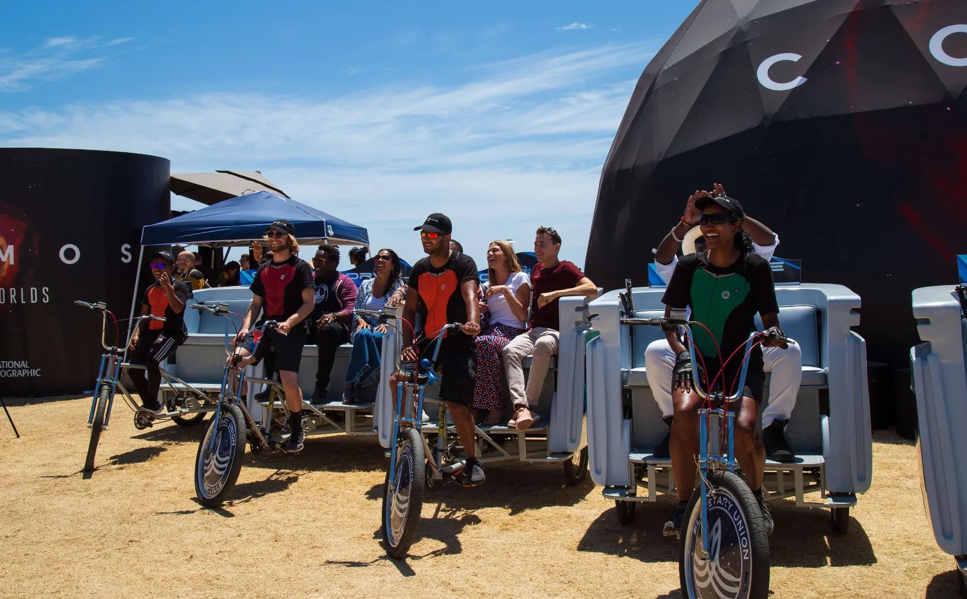 Passengers riding Orville pedicab in front of COSMOS Possible Worlds dome