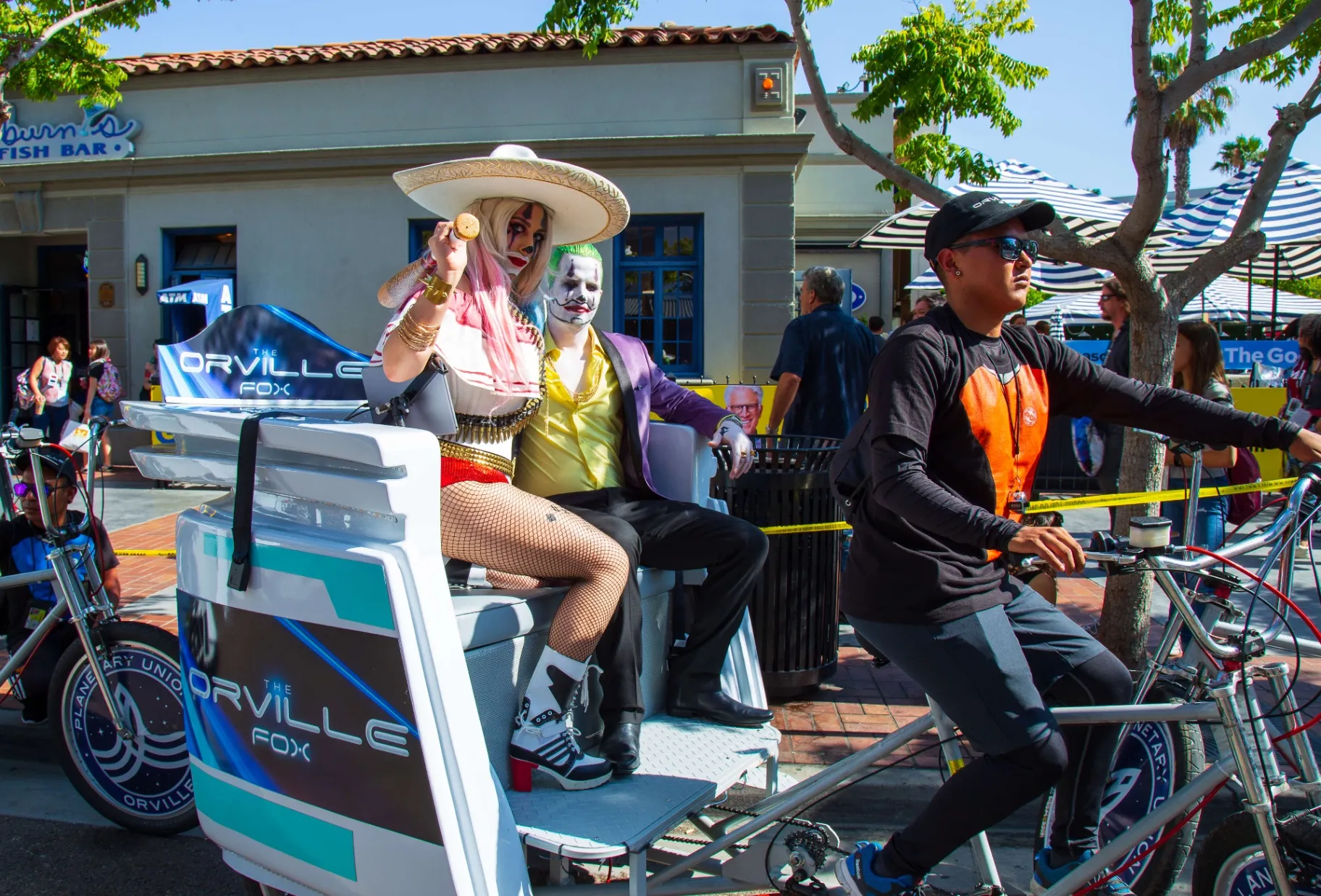 Harley Quinn and Joker cosplayers riding The Orville pedicab at Comic-Con